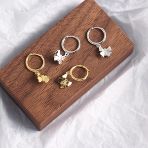 Detailed view of silver and gold butterfly hoop earrings on a dark wooden block
