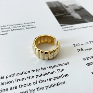 Détail d'une bague ajustable dorée avec une texture de rayures verticales de style rétro