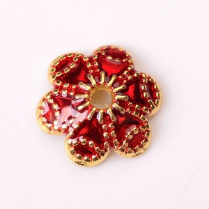 Détail macro d'une perle fleur en émail rouge avec bords dorés pour bijoux artisanaux