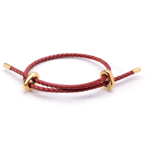 Détail d'un bracelet en cordon rouge tressé avec anneaux de réglage en métal doré
