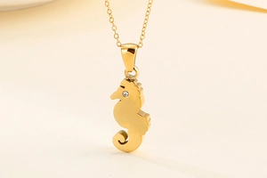 Dettaglio di una collana con ciondolo a forma di cavalluccio marino dorato con cristallo