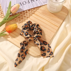 Close-up of leopard print bow hair scrunchie on decorative tray with floral accents