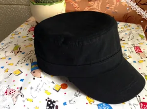 Close-up of a black cotton flat top military cap featuring metallic rivet details