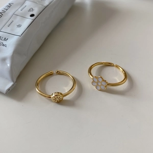 Flat lay of two gold-plated daisy flower and sunburst disc adjustable rings set