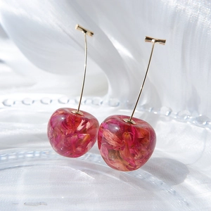 Elegant cherry-shaped earrings with purple dried flowers inside resin on white silk