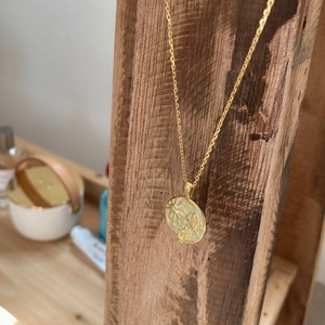 Detail of gold sun and star embossed pendant hanging on a rustic wooden pole