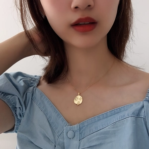 Close-up of a 925 silver coin necklace with sun and star motif on a female model