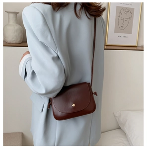 Detail view of small dark brown PU leather crossbody bag with knot shoulder strap on model