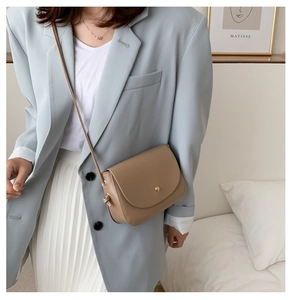 Detail of khaki leather crossbody bag featuring gold metal buckle and knot strap design