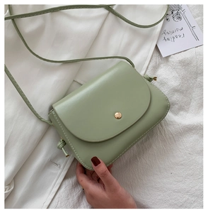 Detail of light green PU leather mini crossbody bag with a golden circular metal buckle