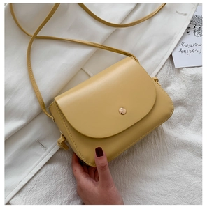 Top-down view of a minimalist yellow square crossbody bag with a golden magnetic buckle clasp