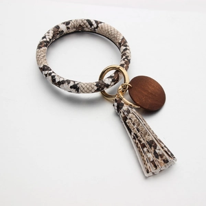 Detail van armband-sleutelhanger met slangenpatroon, kwastje en houten ronde hanger
