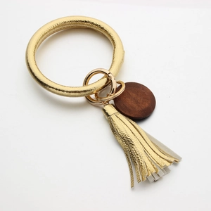 Detail van gouden lederen armband sleutelhanger met PU-kwastje en houten hanger