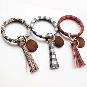 Detailed view of leather tassel keychains in snake skin, black and red plaid patterns