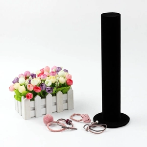 Black velvet cylinder jewelry stand for hairbands and bracelets on white background