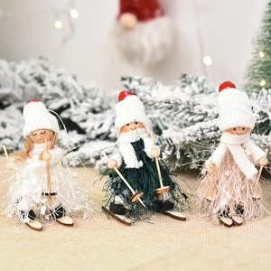 Three plush Christmas skiing dolls with knit hats and wooden skis on a snowy festive base