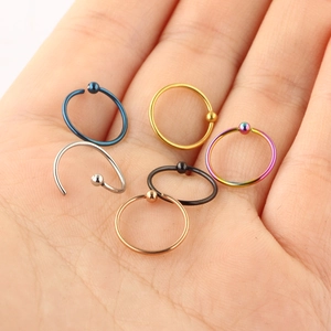 Macro view of six multicolored stainless steel piercing rings held in hand palm