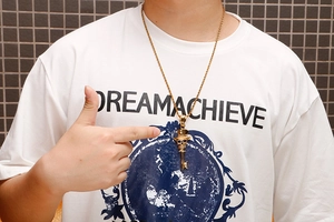 Close-up of golden skull and key pendant necklace on model in punk hip-hop style