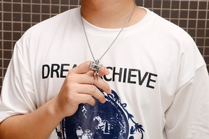 Close-up of a silver angel wing pendant with detailed carving on a twisted rope chain
