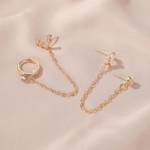 Detail of gold chain earring set with white zircon and pearl on champagne silk