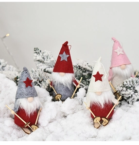Detail of four colorful plush Christmas gnomes with wooden skis on artificial snow