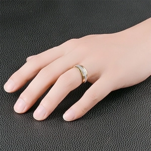 Men's matte titanium steel ring in gold and silver, worn on finger against black leather
