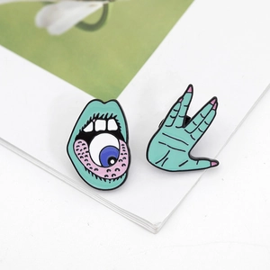 Detail of creative punk enamel pins featuring green hand and mouth with eyeball