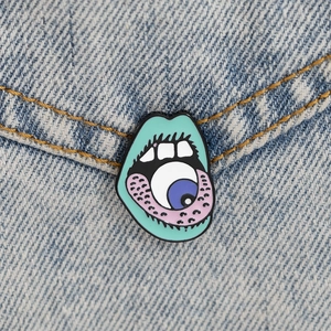Macro shot of surrealist mint green mouth enamel pin with eye detail on denim