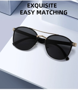 Detailed view of black oval sunglasses with double gold metal bridge and luxury accents