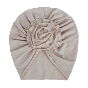 Détail du turban beige en tricot pour bébé avec une grande fleur en tissu 3D