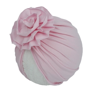 Vue détaillée du bonnet turban rose pour bébé avec une grande fleur en tissu 3D