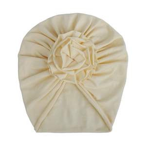 Détail du turban pour bébé en tricot crème avec une grande fleur en tissu superposée