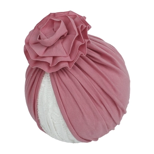 Détail du bonnet turban rose pour bébé en tricot plissé avec une grande fleur en 3D