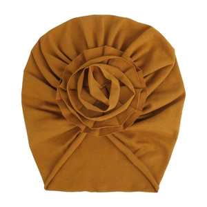 Détail du bonnet turban bébé jaune moutarde avec une grande fleur en tissu doux