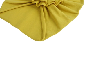Gros plan du bonnet bébé jaune gingembre montrant les détails plissés et la maille coton