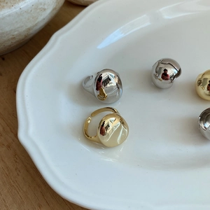 Modern gold and silver irregular liquid-style rings on a white ceramic display tray