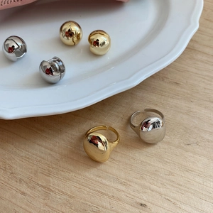 Detail of 925 sterling silver open rings and ball earrings on a white ceramic tray