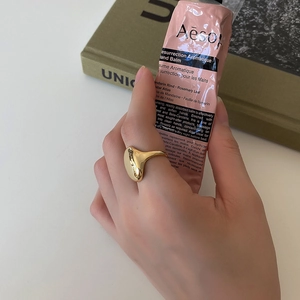 Detail of high-polished gold irregular curved ring worn by model with minimalist style