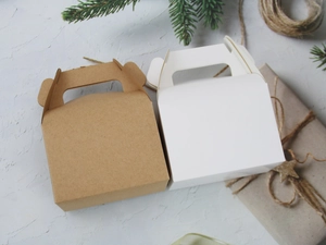 Detailed view of brown kraft and white cardboard gift boxes with festive pine decoration