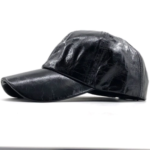 Detail of black PU leather baseball cap showing glossy wrinkled texture and stitching