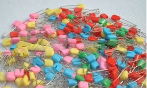 Dettaglio di spille da balia colorate con testa in plastica per cucito e artigianato DIY