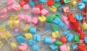 Dettaglio di spille da balia colorate in plastica per abbigliamento neonato e cucito