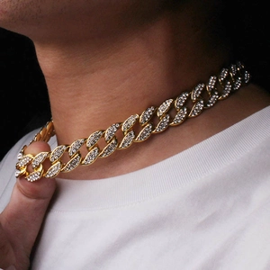 Close-up of men's gold plated Cuban link necklace with sparkling crystals on model
