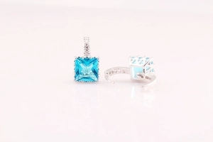 Detailed close-up of square blue zircon earrings with silver hoop and micro-pave setting