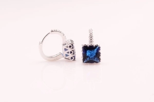 Close-up of square blue zircon inlay and sparkling pave diamonds on silver hoop earrings