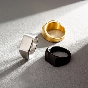 Detailed view of brushed stainless steel signet rings in gold, silver, and black finishes
