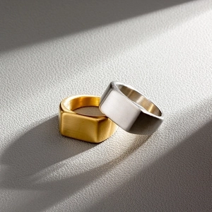 Macro detail of rectangle signet rings in gold and silver finish with brushed metal texture