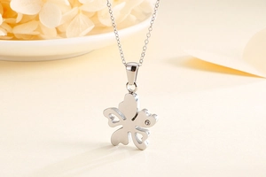 Gros plan d'un collier trèfle argenté avec cristal sur un fond floral élégant