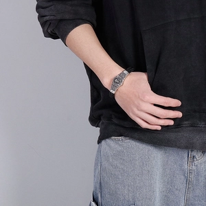 Close-up of men's braided leather bracelet featuring an embossed silver metal clasp