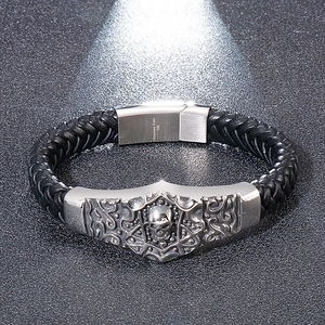 Detail of black braided leather bracelet with silver skull charm and 316L steel clasp